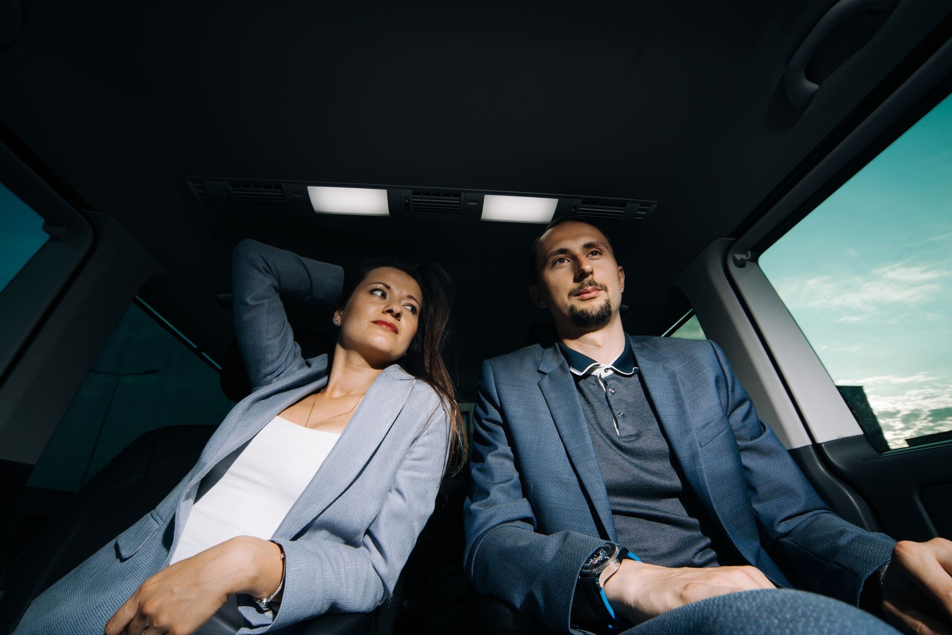 Business man and woman travellng in vip car transfer. Couple in the backseat of luxury minivan